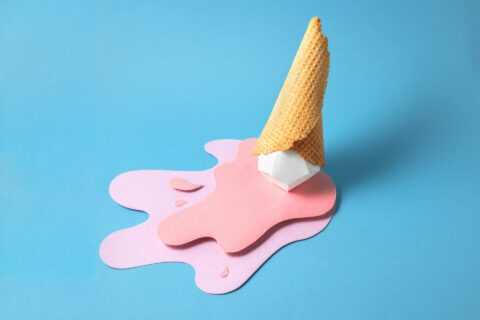 Artistic depiction of a dropped and melting strawberry ice cream cone against a light blue background.