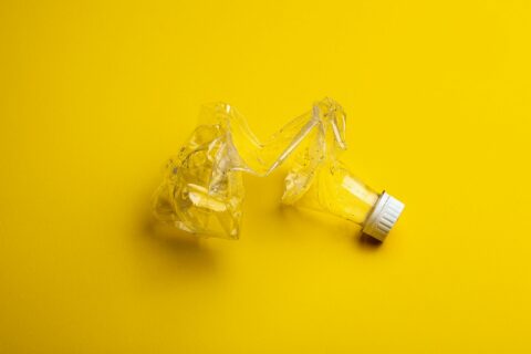 Crushed and melted light bulb against a yellow background