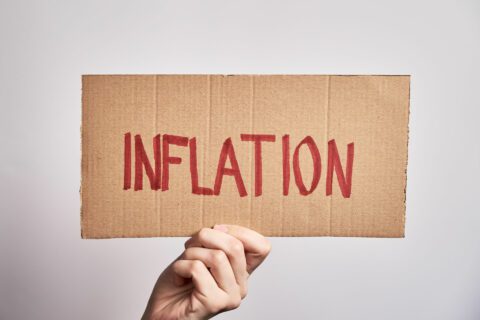 Cardboard sign with the word “inflation” written on it in red ink.
