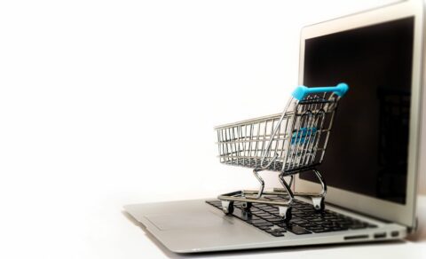 A miniature shopping cart sitting on a laptop keyboard